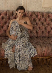 Model seated on a tufted pink patterned sofa wearing a blue and white floral dress for Elle Australia