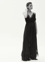 Model Aria Shine wearing a long black lace-trimmed gown against a seamless white studio background for Elle Australia.