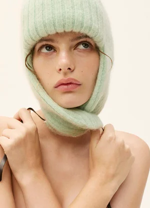 Model wearing a ribbed pale green knit balaclava against a plain light background for Elle Australia