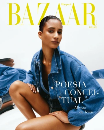 Fashion magazine cover featuring a woman with dark hair, wearing a denim jacket, posing in front of a white backdrop with mirrored reflections.