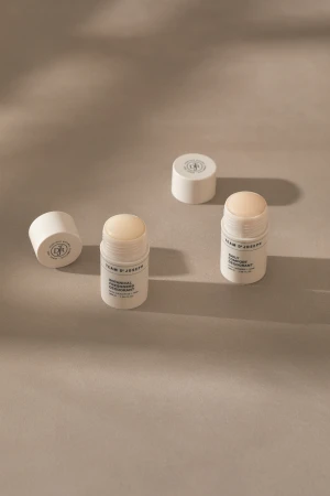 Four white tubes of Team D'Joseph deodorant, two with caps, are arranged on a neutral surface with soft shadows.
