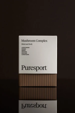Puresport Mushroom Complex product box on reflective surface against dark backdrop in a studio setting. Health, wellness concept.