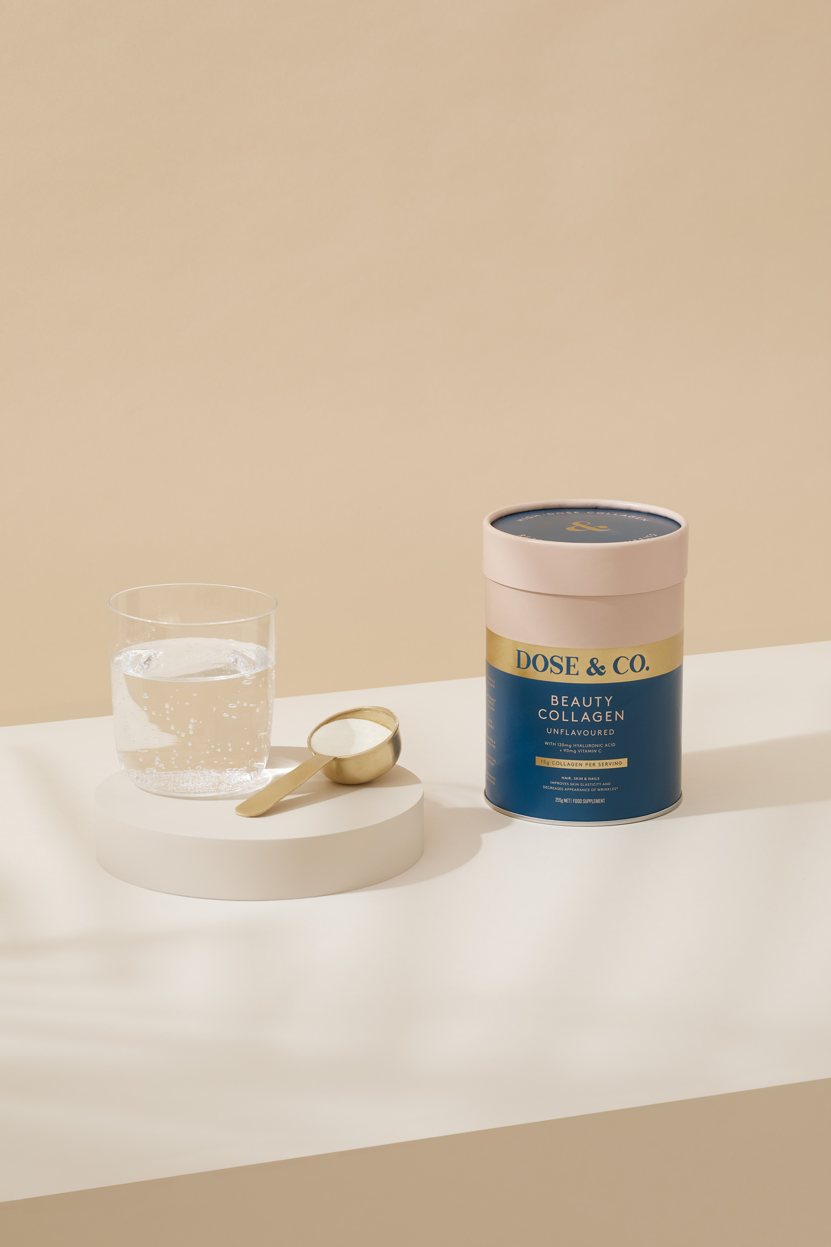 Product shot of Dose & Co. Beauty Collagen supplement with a scoop and glass of water, featuring a clean, minimalist aesthetic.