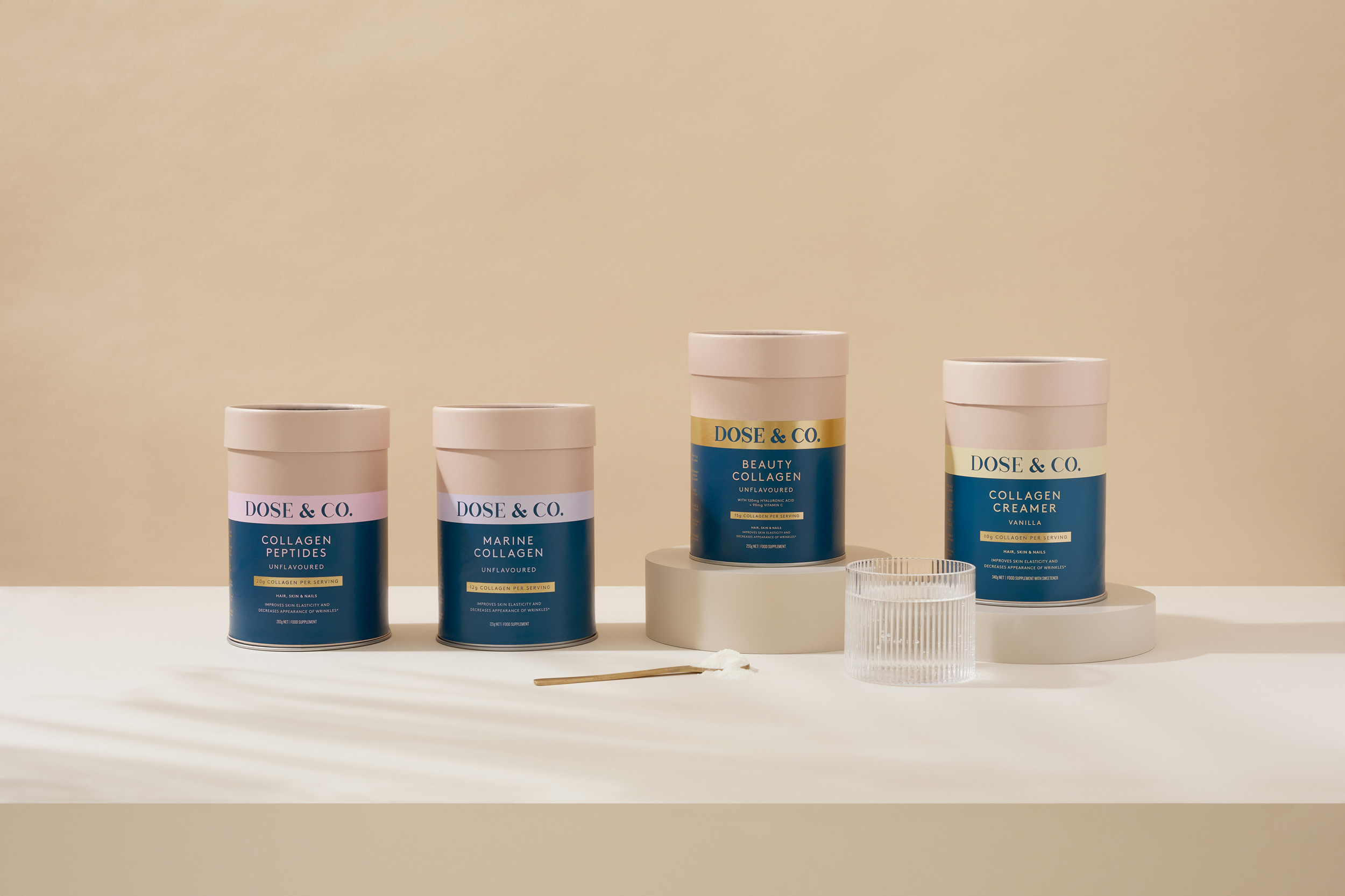Four cans of Dose & Co collagen supplements are arranged on a table with a small container and stick in a minimalist scene.
