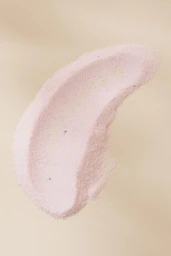 A curved smear of pale pink textured powder on a smooth beige neutral background.