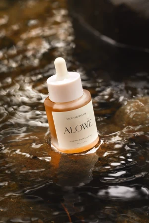 Close-up of golden serum bottle with dropper in shimmering water. Beauty product and skin care concept for online marketing.