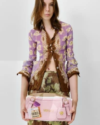 Model wearing a patterned purple shirt holding a pink designer handbag in a studio fashion shoot for Special Delivery.