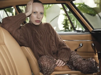 Model seated on wooden chair wearing a fuzzy grey mohair sweater and black leather boots for sass and bide.