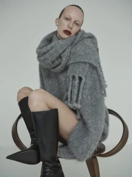 Model seated on wooden chair wearing a fuzzy grey mohair sweater and black leather boots for sass and bide.