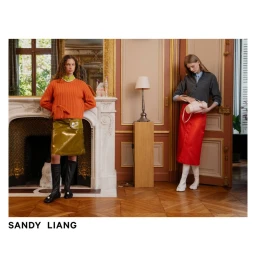 Two fashion models posing in an ornate room wearing colourful skirts, knitwear, and knee-high boots for Sandy Liang.