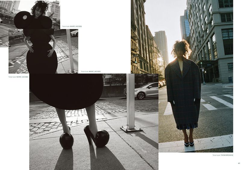 Fashion editorial featuring a Black model in a stylish dress and coat on a city street, showcasing bold silhouette and urban setting.