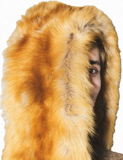 Portrait of a woman with one eye visible, wearing a shaggy orange faux fur hood. The background is white.