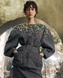 Model in embellished plaid coat with crystal beadwork on shoulders looking down