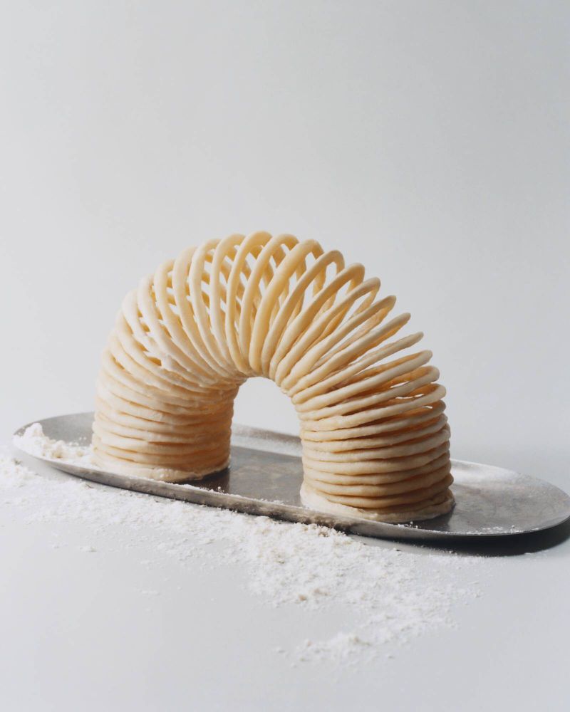 Slinky toy on a reflective silver tray, photographed in a light and airy studio setting against a plain white backdrop.