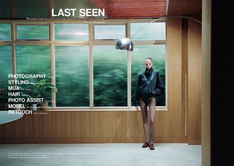 Fashion editorial shot of a slender adult female model in a black leather jacket in an indoor wood-paneled setting with a large window.
