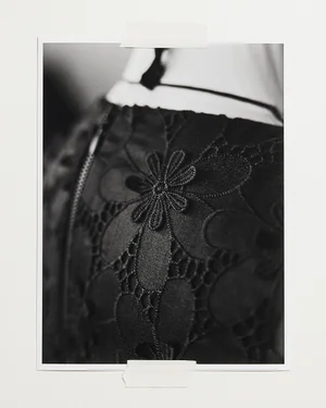 Monochrome close-up of dark floral lace dress taped to a plain background for Veronika Maine.