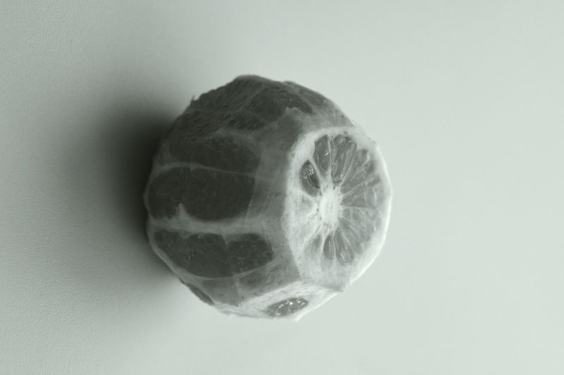 Monochrome image of a peeled grapefruit with a distinctive texture on a plain background, offering a fresh and simple still life.
