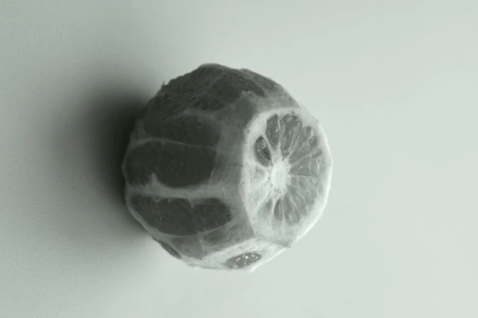Monochrome image of a peeled grapefruit with a distinctive texture on a plain background, offering a fresh and simple still life.