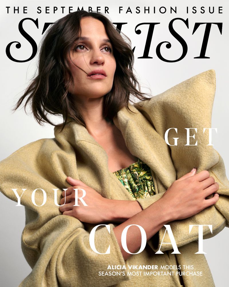 Alicia Vikander on the cover of Stylist September Fashion Issue wearing an oversized beige coat, with text overlay. 