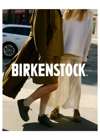 Two people wearing Birkenstock shoes and clothing in an outdoor urban setting, featuring the brand logo in a fashion advertisement.