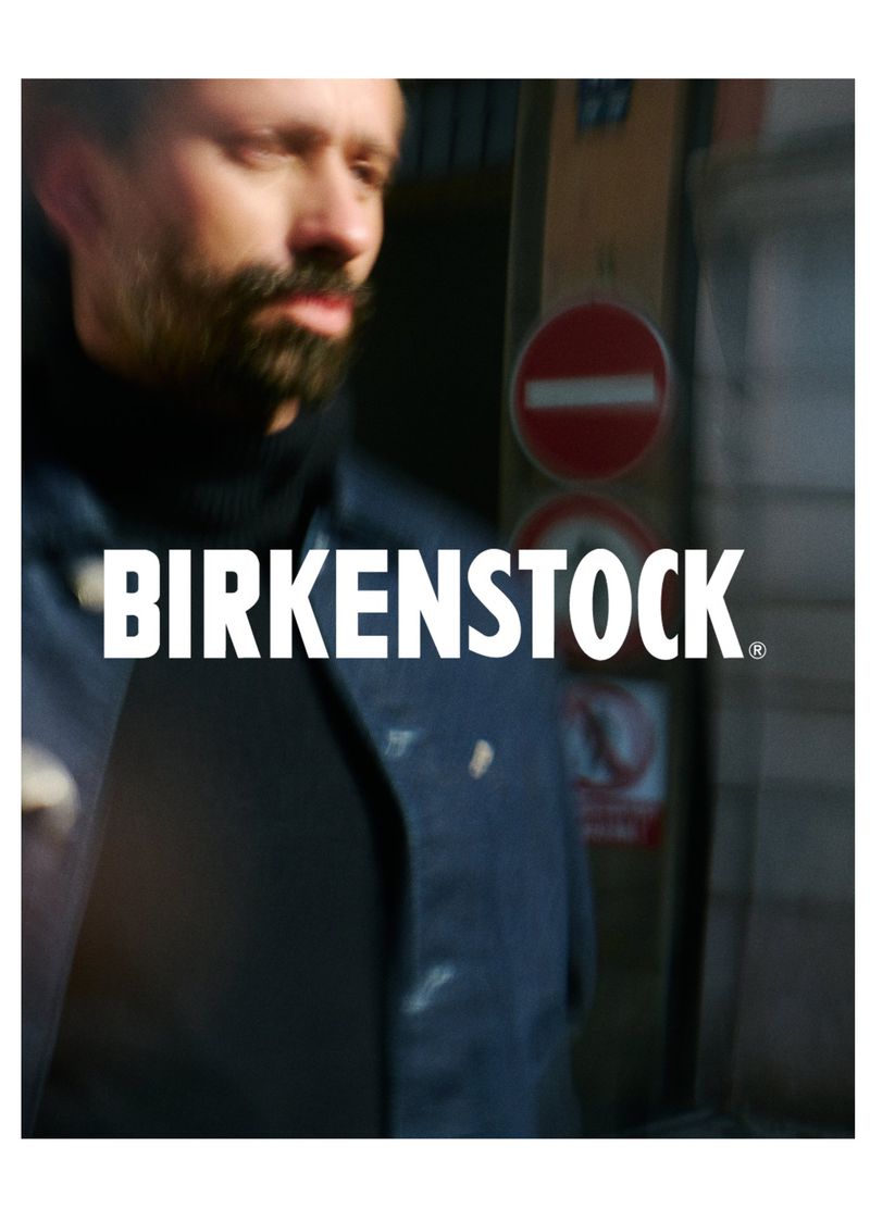 Adult male in an outdoor urban setting wearing a dark blue jacket and black turtleneck with Birkenstock logo visible in the center.