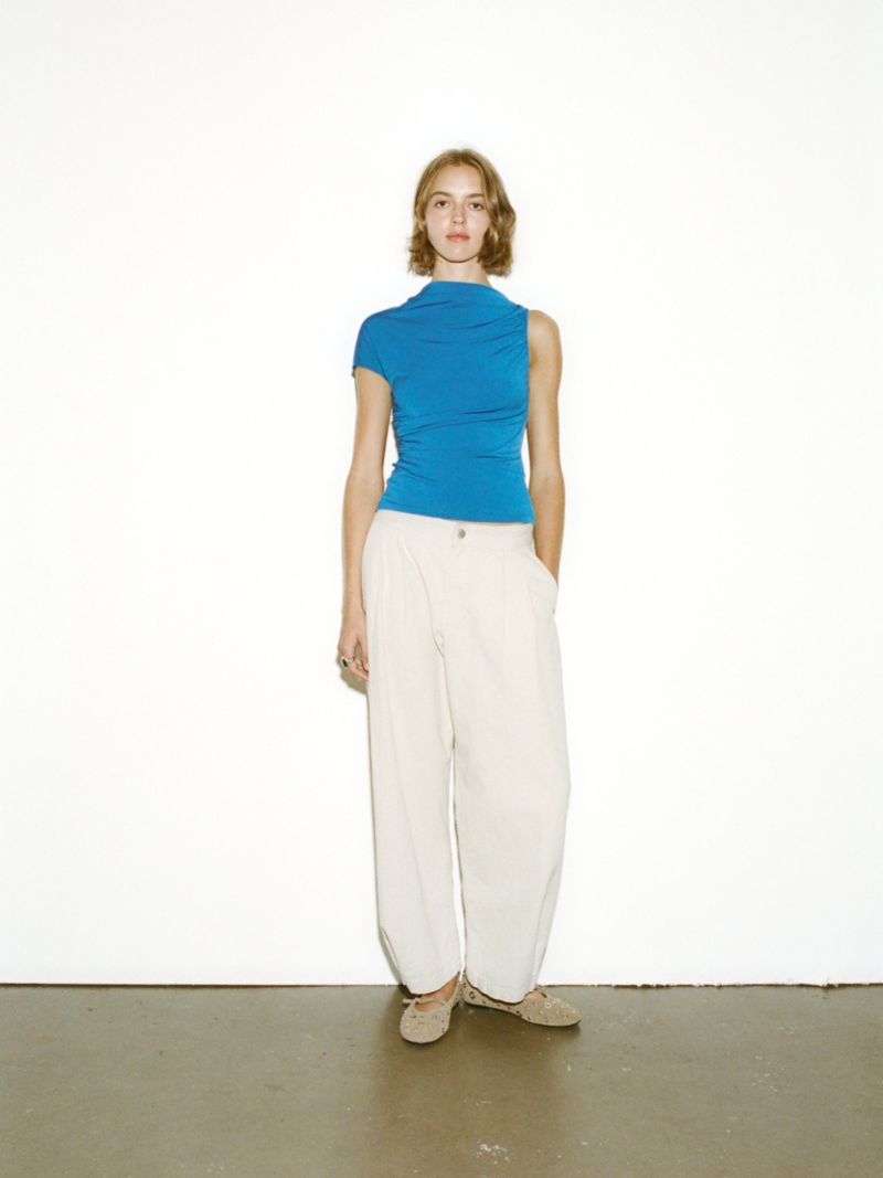 Model standing against a white wall wearing a blue top and white trousers photographed by Xabin Zabala for Pull & Bear.