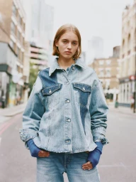 Model wearing a paneled denim jacket and matching jeans on a city street shot by Xabin Zabala for Pull & Bear