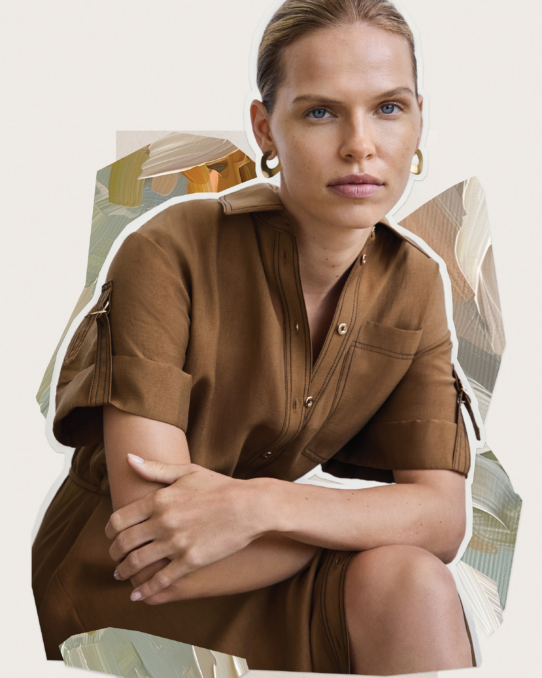 Close-up of a blonde woman in a brown collared dress with gold hoop earrings, posing against a neutral background with painted shapes.