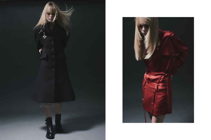 Two fashion models in a studio setting; one wears a long black coat and boots, the other a red dress with dark background.