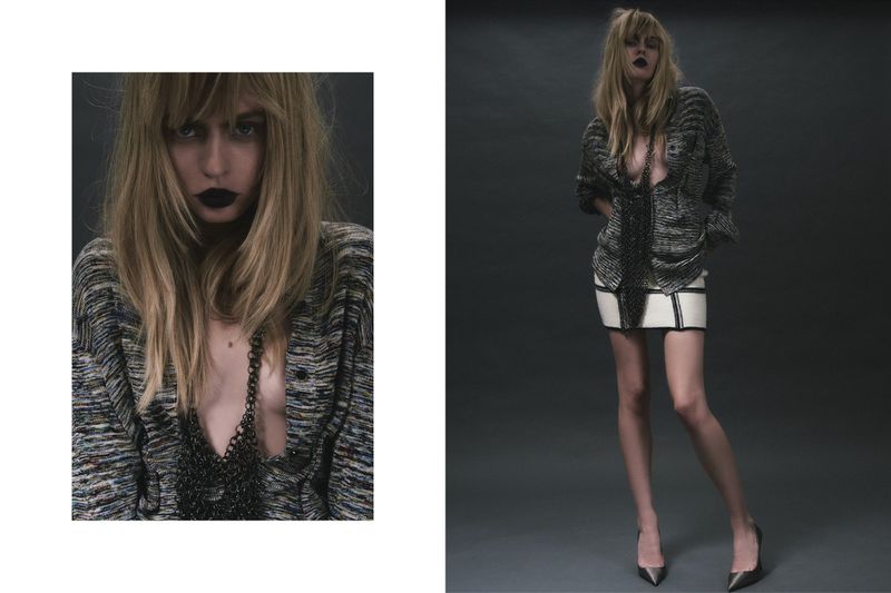 A woman in a knit shirt, white skirt, and heels poses in a studio, showcasing a fashion editorial look with dramatic, dark makeup.