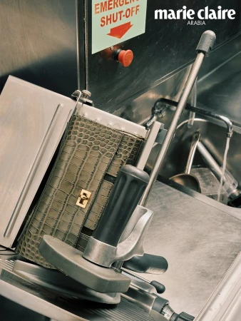 Marie Claire Arabia fashion shot: Leather purse on a slicer against a metallic background with an emergency shut-off switch.