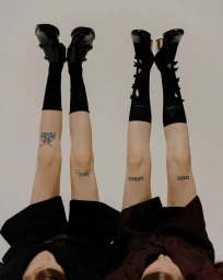 Two models with legs raised in the air wearing black socks and shoes against a neutral background for Marie Claire Czech Republic.