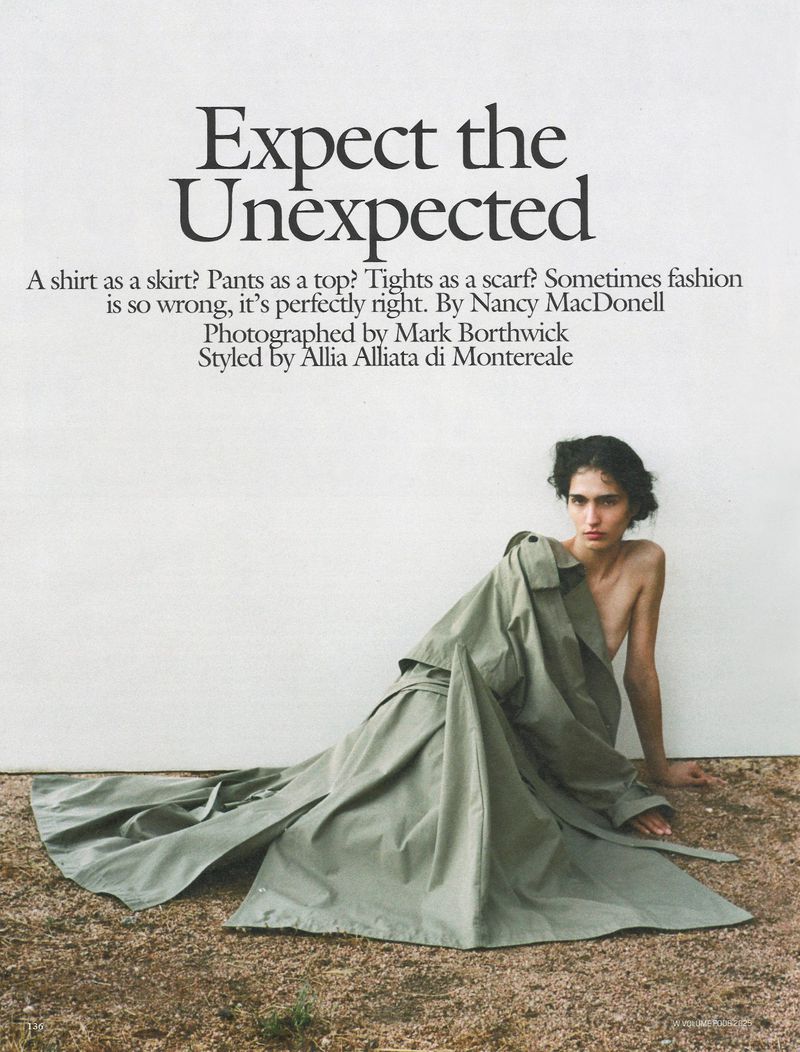A young adult poses in a sage-green trench coat against a white wall, accented by earthy-toned ground and editorial typography.