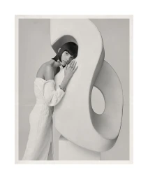Model Charlee Fraser wearing a white dress posing with a large sculptural white form for Harper's Bazaar Australia