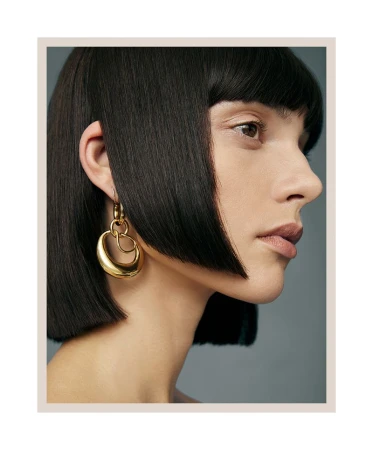 Close-up portrait of a woman with sharp dark bob wearing sculptural gold earrings for Harper's Bazaar Australia.