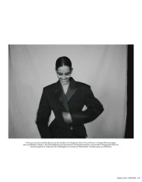 Model wearing a tailored black blazer with structured shoulders against a seamless white background.