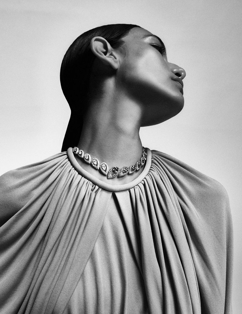 Model Nour Rizk wearing a sparkling teardrop jewel necklace and draped pleated gown in profile for Vogue Arabia.