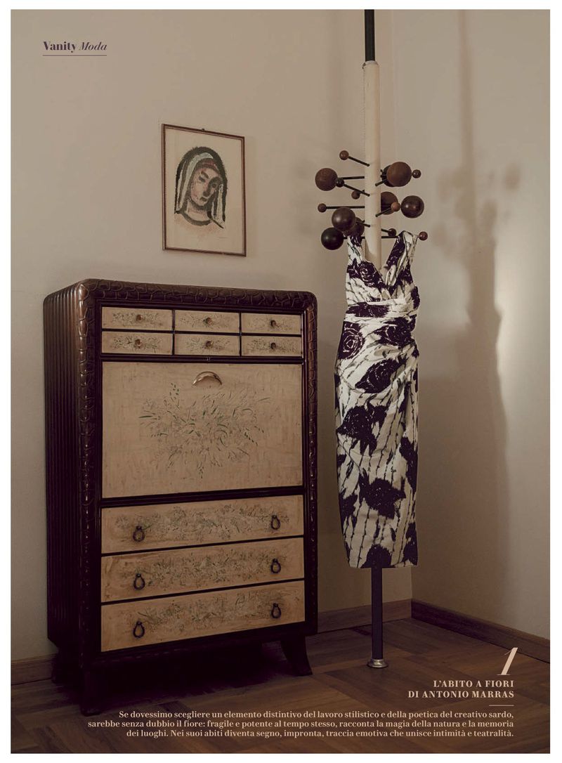Vintage interior scene showcasing a patterned dress on a coat rack, an antique cabinet, and an art portrait on a light-colored wall.