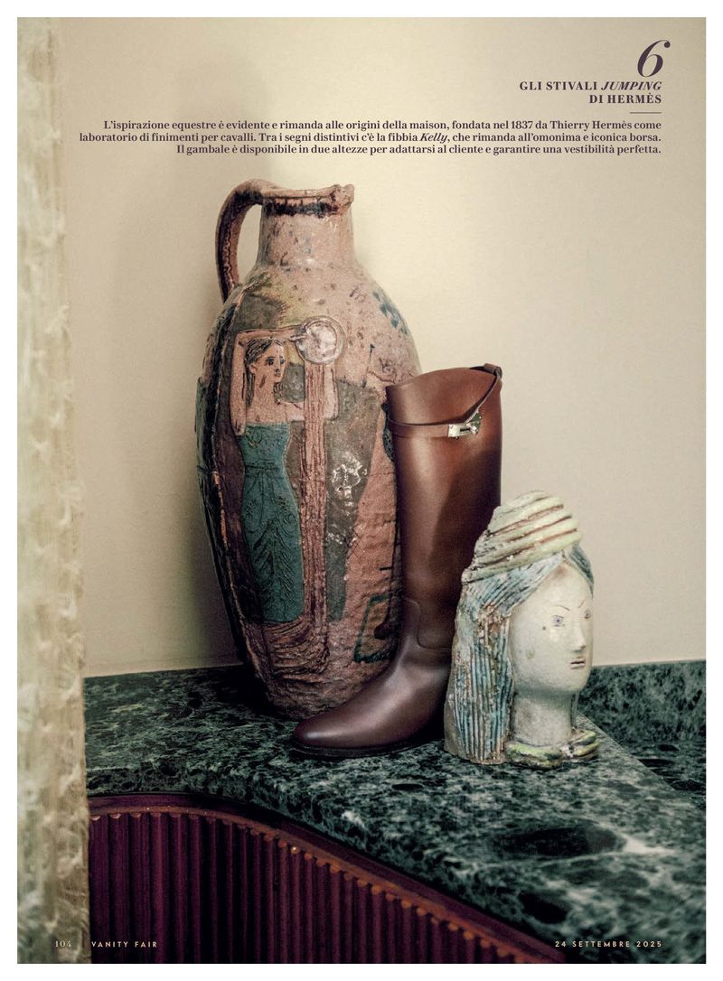 Still life of a brown leather riding boot, an earthenware vase with a figure, and a glazed pottery head on a green marble counter.