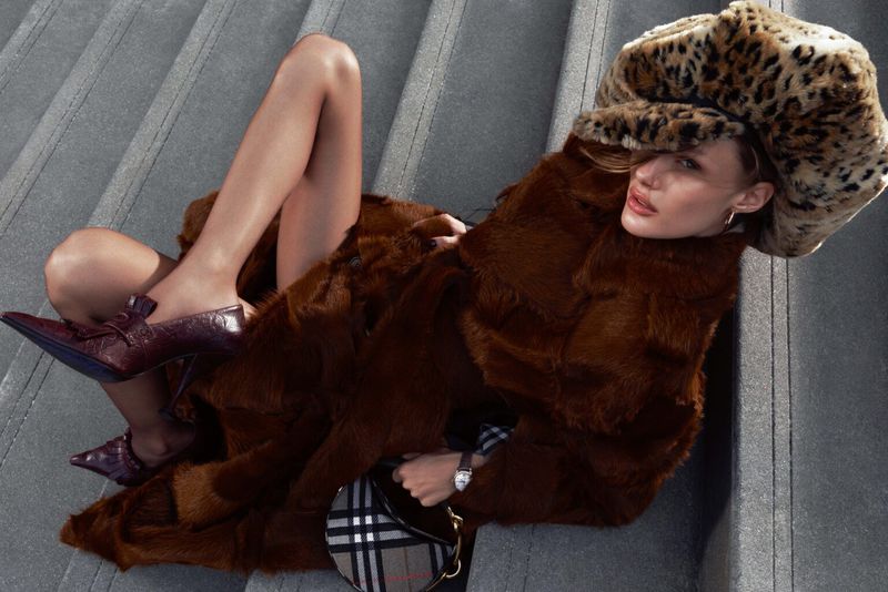 Woman in fur coat and animal print hat lying on grey stairs with designer bag and heels; fashion and style, shot from overhead.