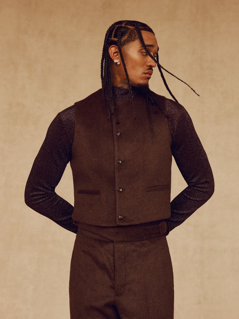 Jordan Clarkson wearing a brown tailored vest over a shimmering long-sleeve shirt against a warm textured studio backdrop.