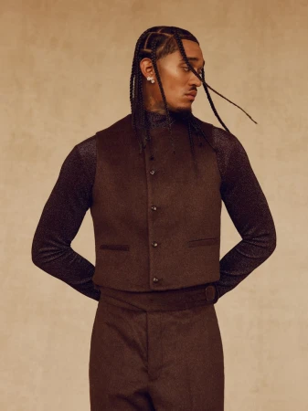 Jordan Clarkson wearing a brown tailored vest over a shimmering long-sleeve shirt against a warm textured studio backdrop.