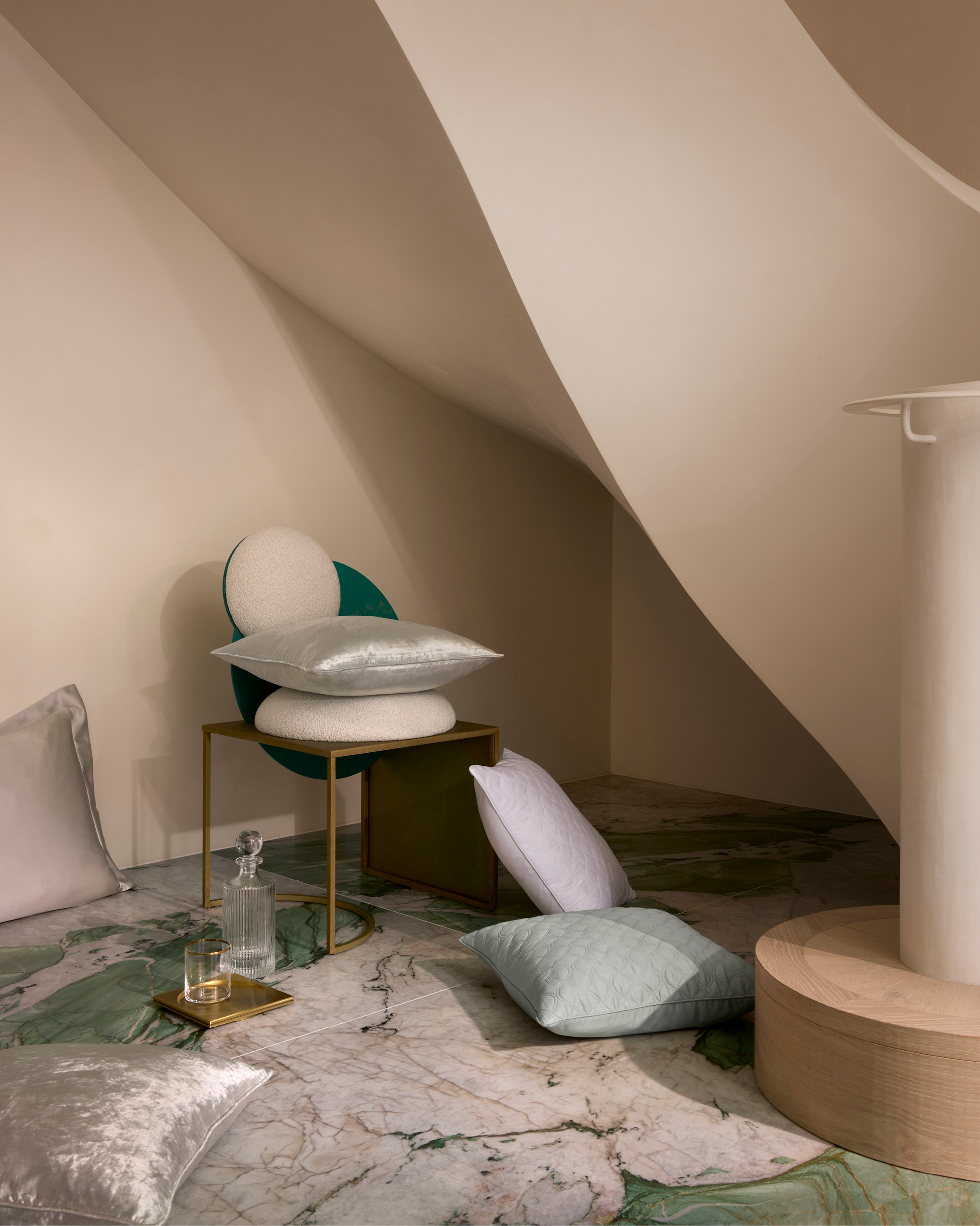 Interior shot with soft lighting featuring assorted decorative pillows on a chair and the marble floor, showcasing a modern, minimalist aesthetic.