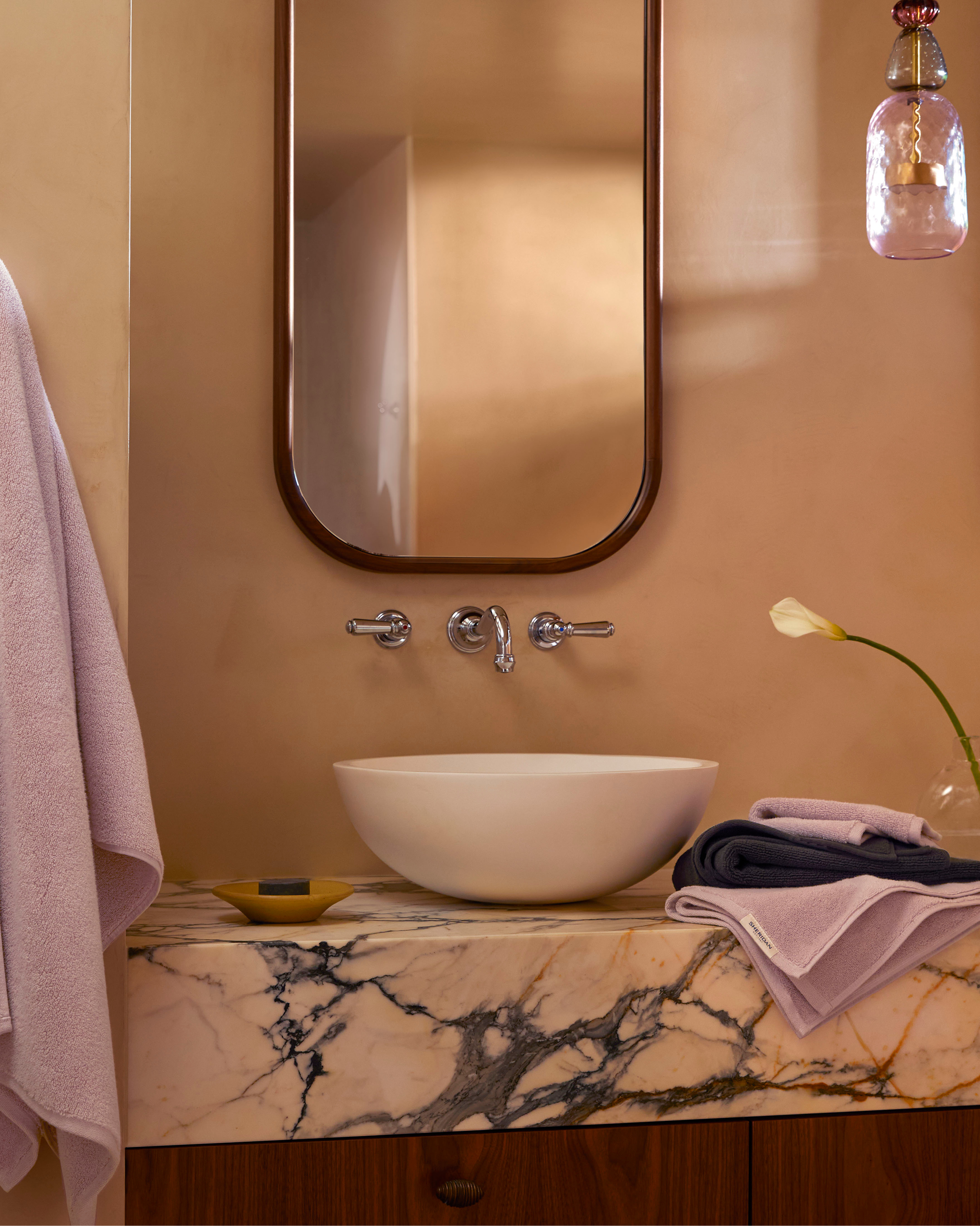 Bathroom interior featuring a white vessel sink, marble countertop, mirror, and a towel, creating a clean and modern aesthetic.