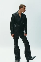 Model Clement Chabernaud in a black leather suit posing against a plain white background for 10 Men Magazine.