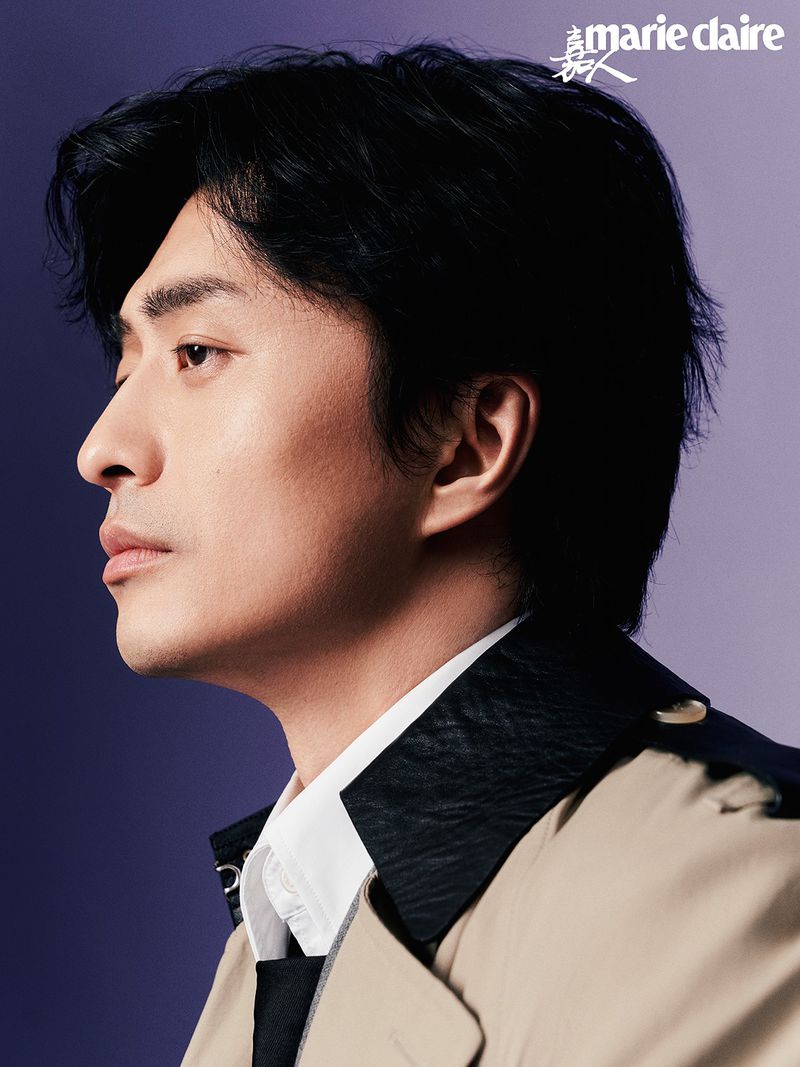 Portrait of an Asian man in a trench coat looking left, with dark hair and a purple background, featuring the 'Marie Claire' logo.