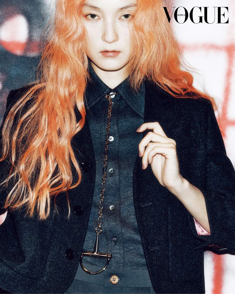 Close-up fashion shot of a fair-skinned adult female model with ginger hair wearing a dark blazer with a silver chain.