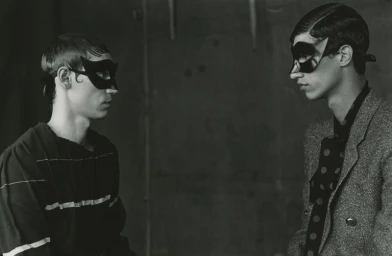 Two men wearing dark eye masks facing each other in a black and white editorial photograph for 10 Men Magazine