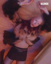 Model lying on wooden floor wearing a furry patterned coat and dark shorts for BLONDE Magazine editorial