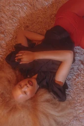 Model lying on a shaggy rug wearing a black top and red leggings for Blonde Magazine editorial.